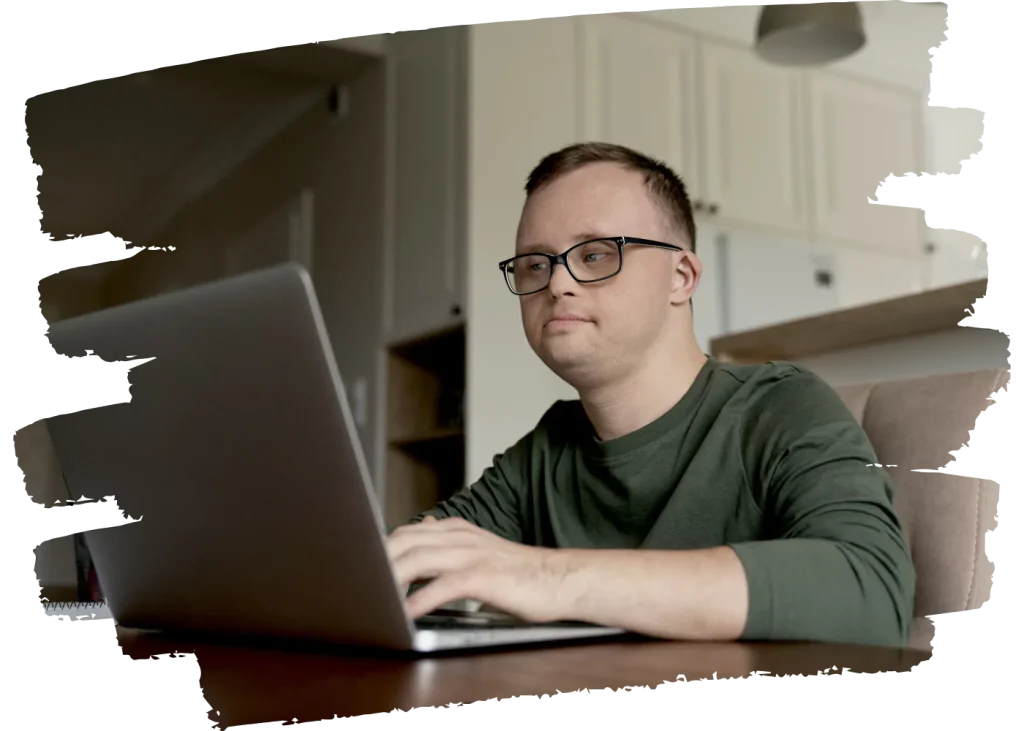 Disabled man with down syndrome using laptop to contact Renaissance Wellness Care