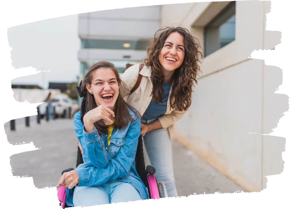 Disabled girl in wheelchair laughing with support worker outside